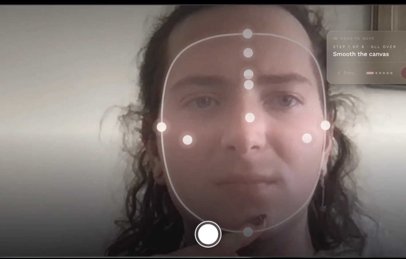 A person looking into a softly lit mirror with translucent rose-gold AR overlays gently guiding makeup placement on their face.